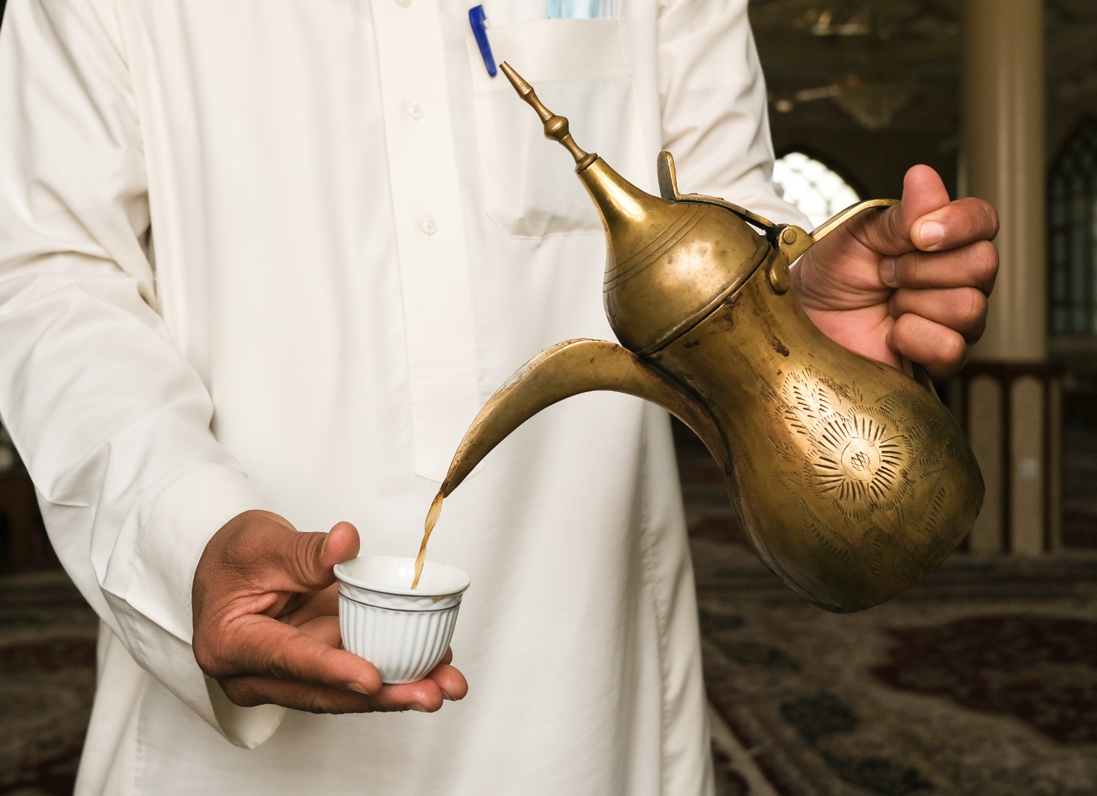Man pouring tea from arabesque looking tea pot